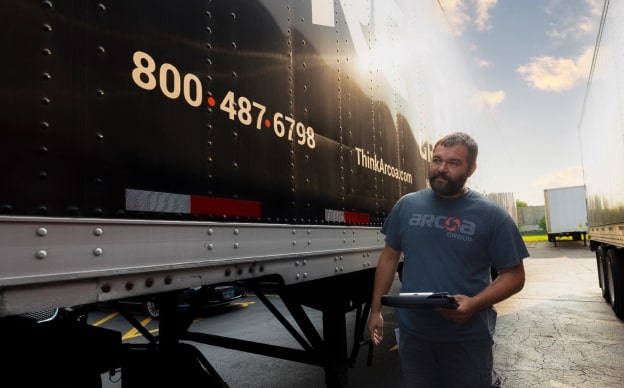 ARCOA employee walking with a tablet between 2 ARCOA trucks