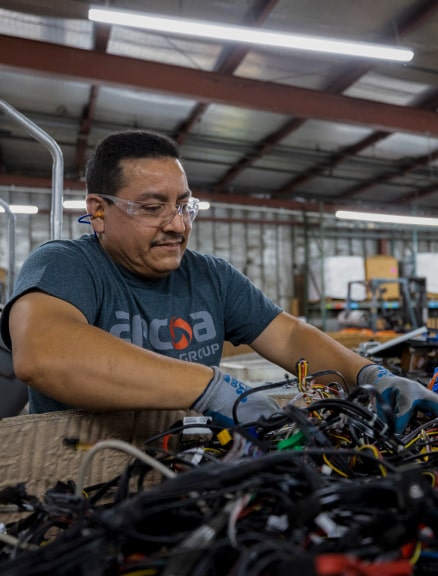 ARCOA employee sorting through large bin of assorted cables in a warehouse