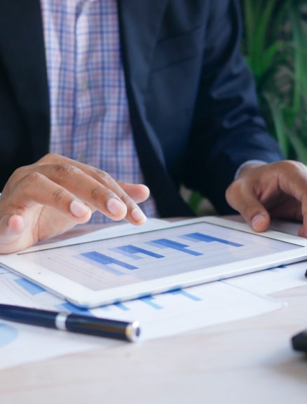 Man interacting with a bar chart on a tablet at his desk