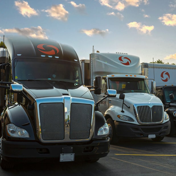 4 ARCOA trucks parked side by side at an angle in outdoor parking lot on a sunny day