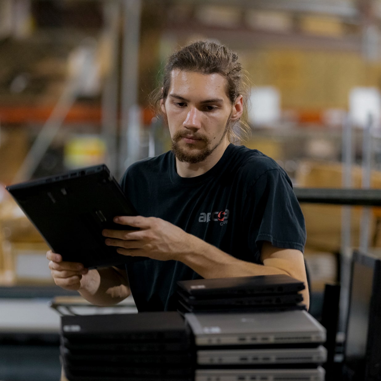 ARCOA employee stacking laptops into piles in a warehouse