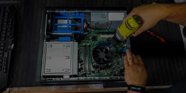 Hands holding a drill and disassembling a computer