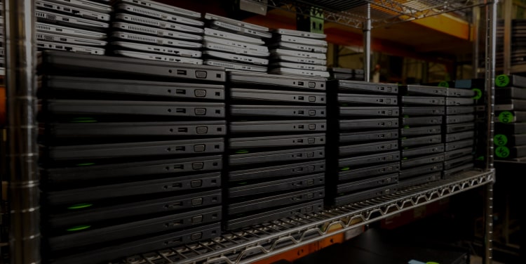 Shelf filled with black laptops stacked on top of each other